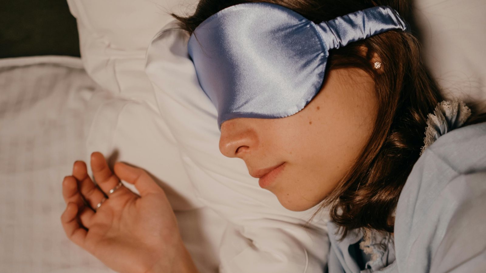 fille avec masque de nuit en soie dormant sur une taie d'oreiller en soie blanche